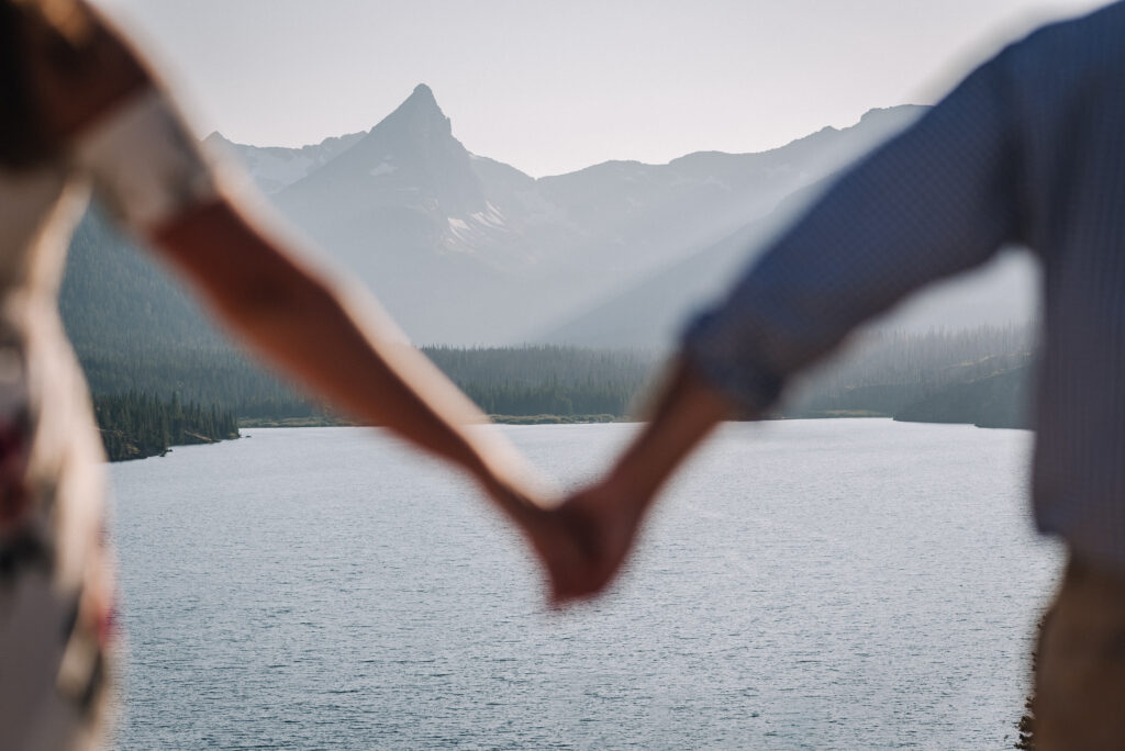 man and woman holding hands in front of mountains in Glacier National Park, Montana