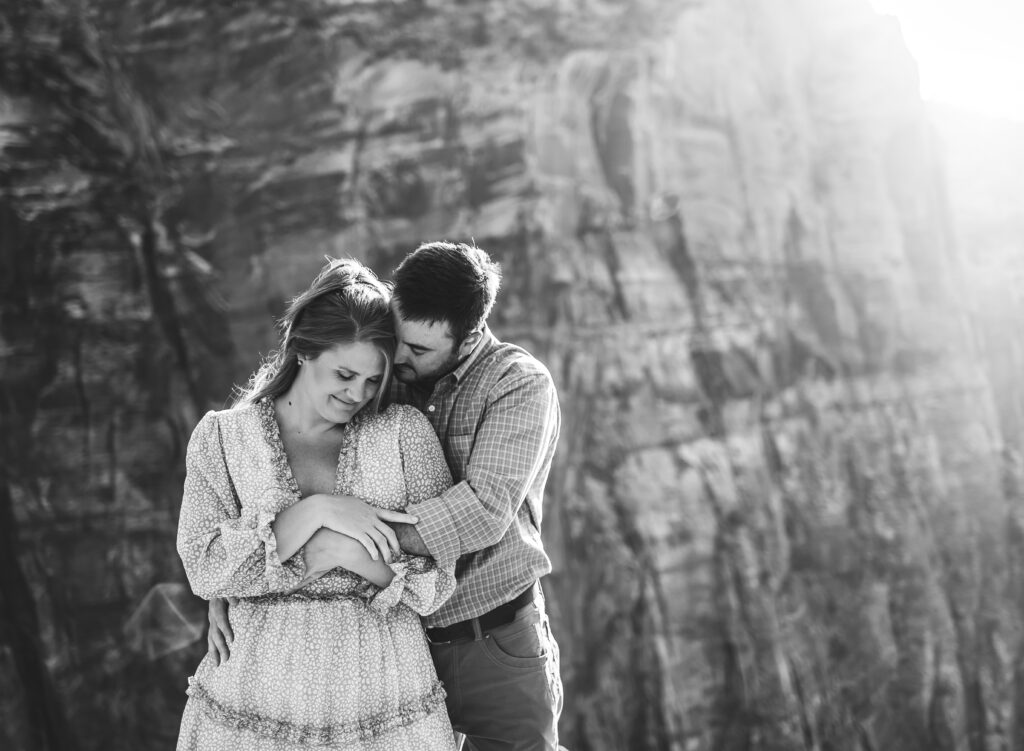 A man and woman on adventure elopement snuggle with a stunning landscape at Zion National Park in the background