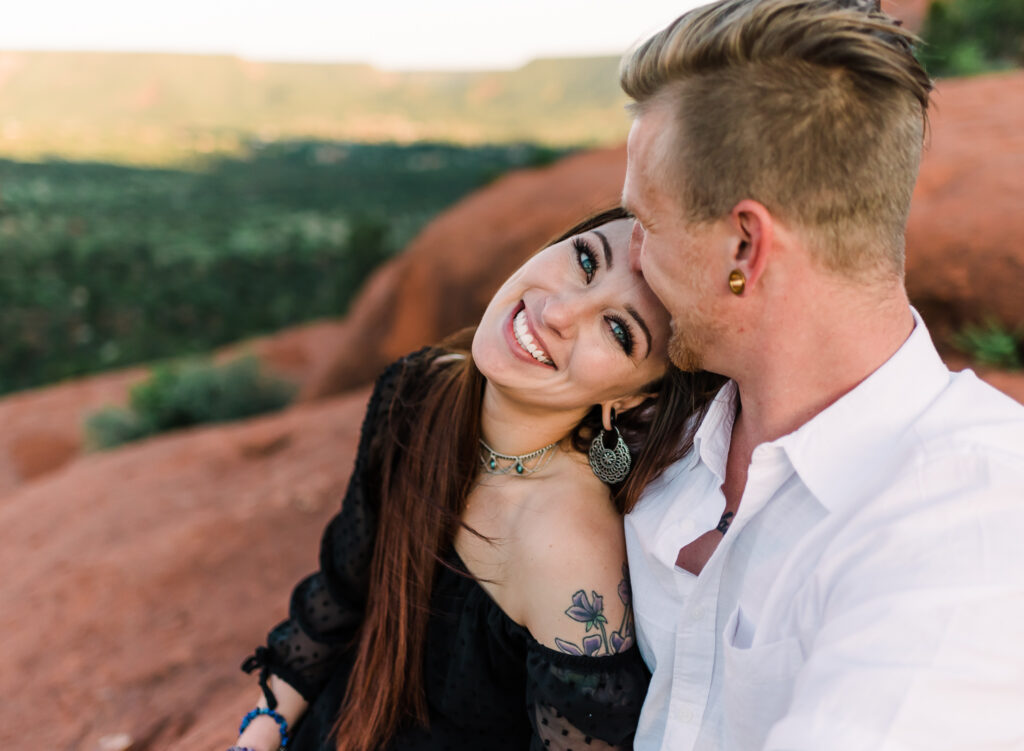 A woman leans her head back on her boyfriend's shoulder and smiles at the camera in Sedona Arizona