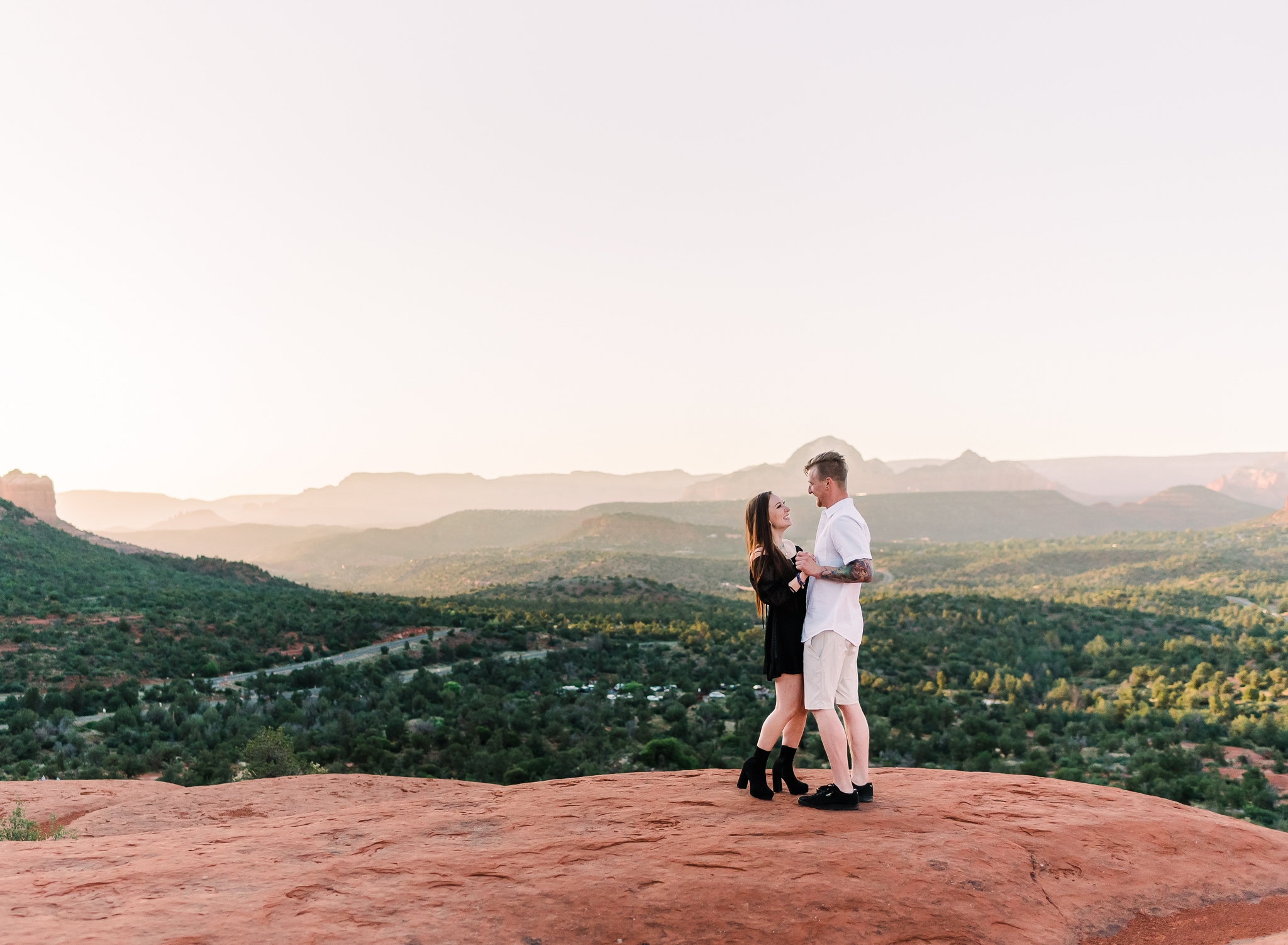 A man and woman dancing at their adventure elopement with sweeping views of Sedona Red Rocks behind them. 