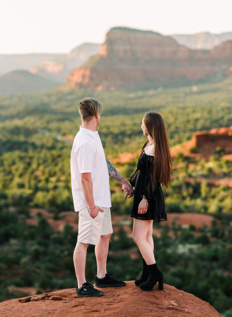 A man and woman hold hands and look out at the view of the Red Rocks in Sedona Arizona