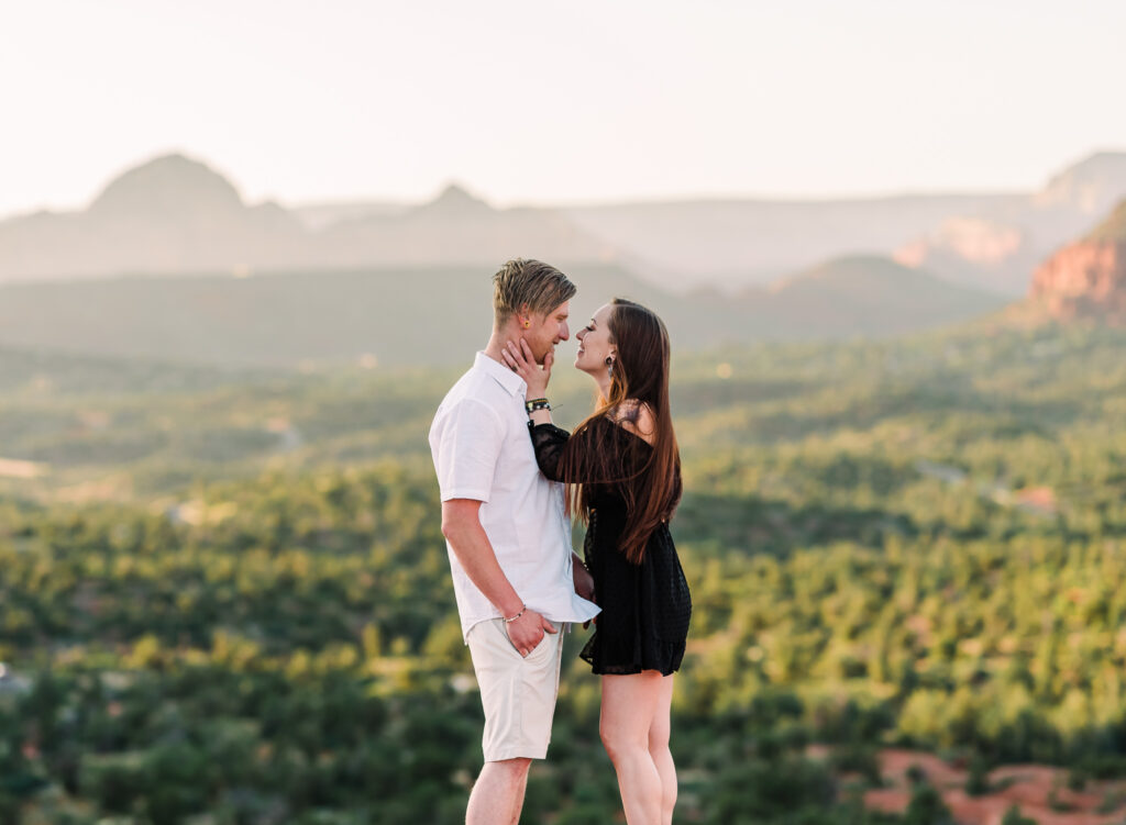 A man and woman almost kiss with the red rocks of Sedona Arizona behind them