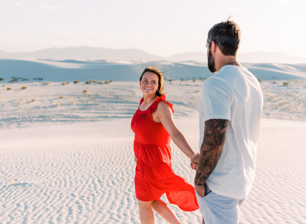 A couple walks hand in hand at White Sands National Park during their couple adventure session