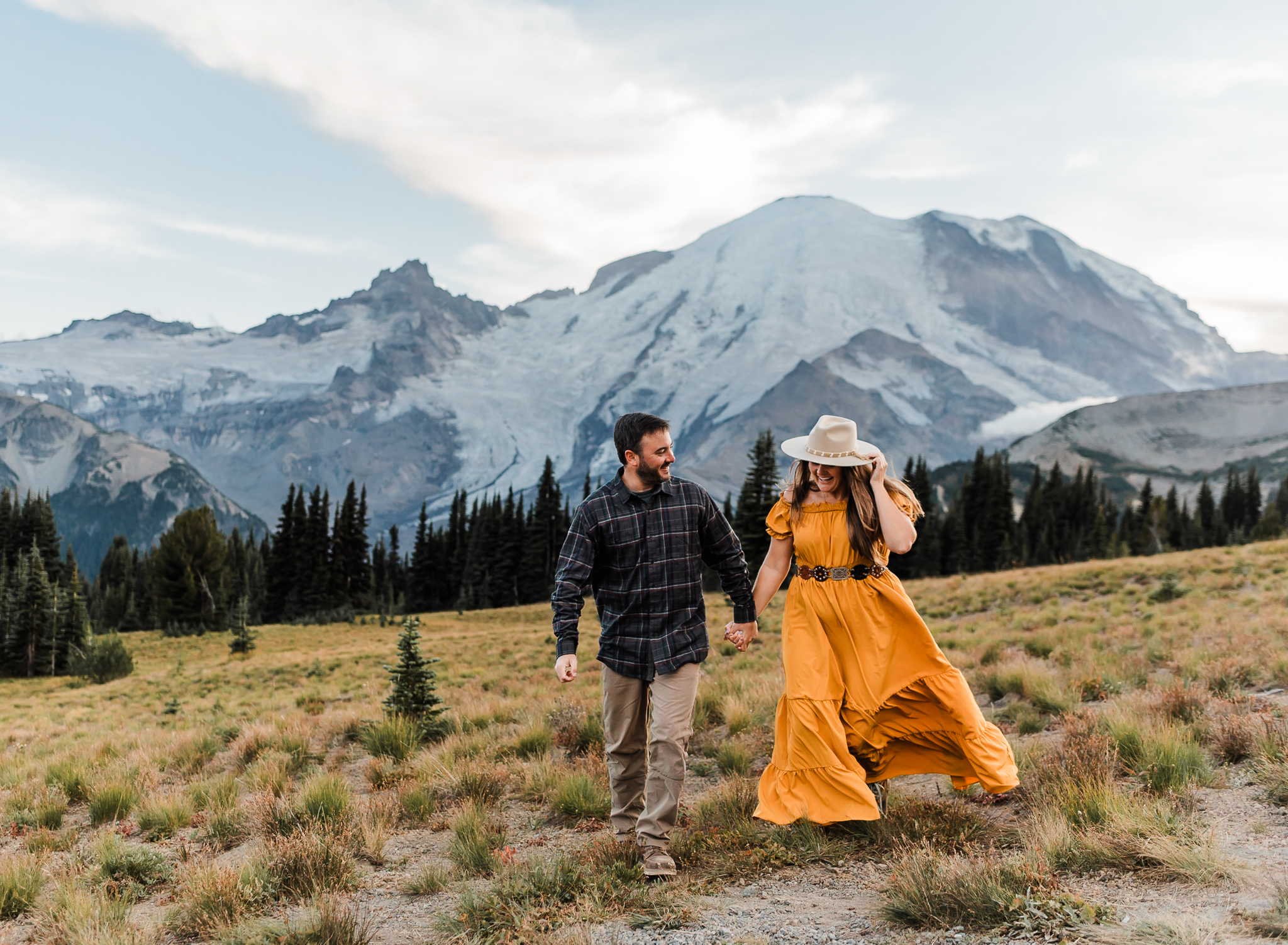 A man and woman run hand in hand
 at their couples adventure session at Mount Rainier National Park 