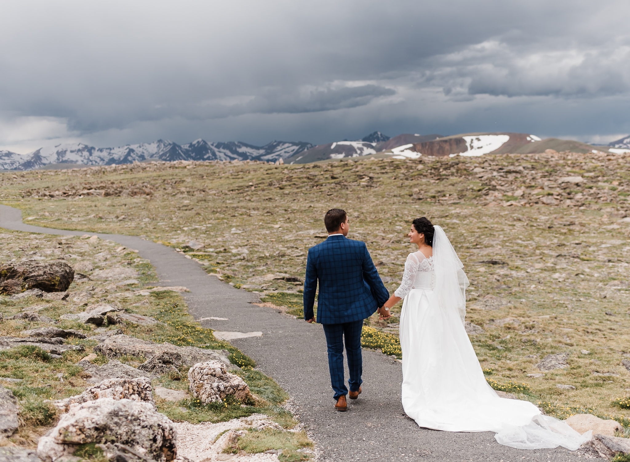 A bride and groom walk away from the camera and towards the mountains that are behind them at their colorado adventure elopement