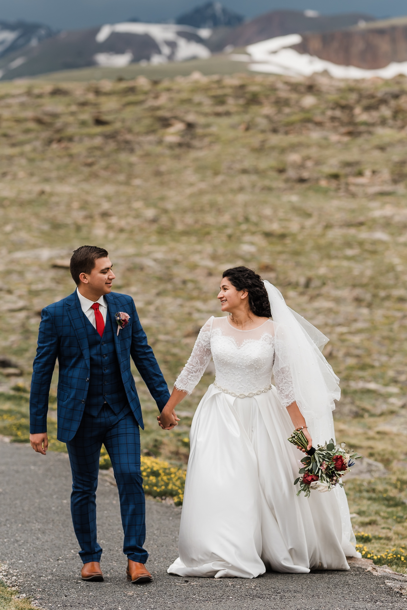 A bride and groom walk hand in hand at their colorado mountain elopement