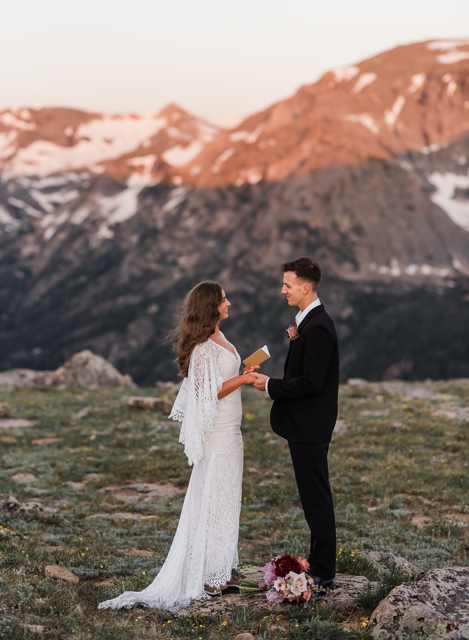 A bride is reading her vows to her groom in front of a large mountain range at Rocky Mountain National Park.