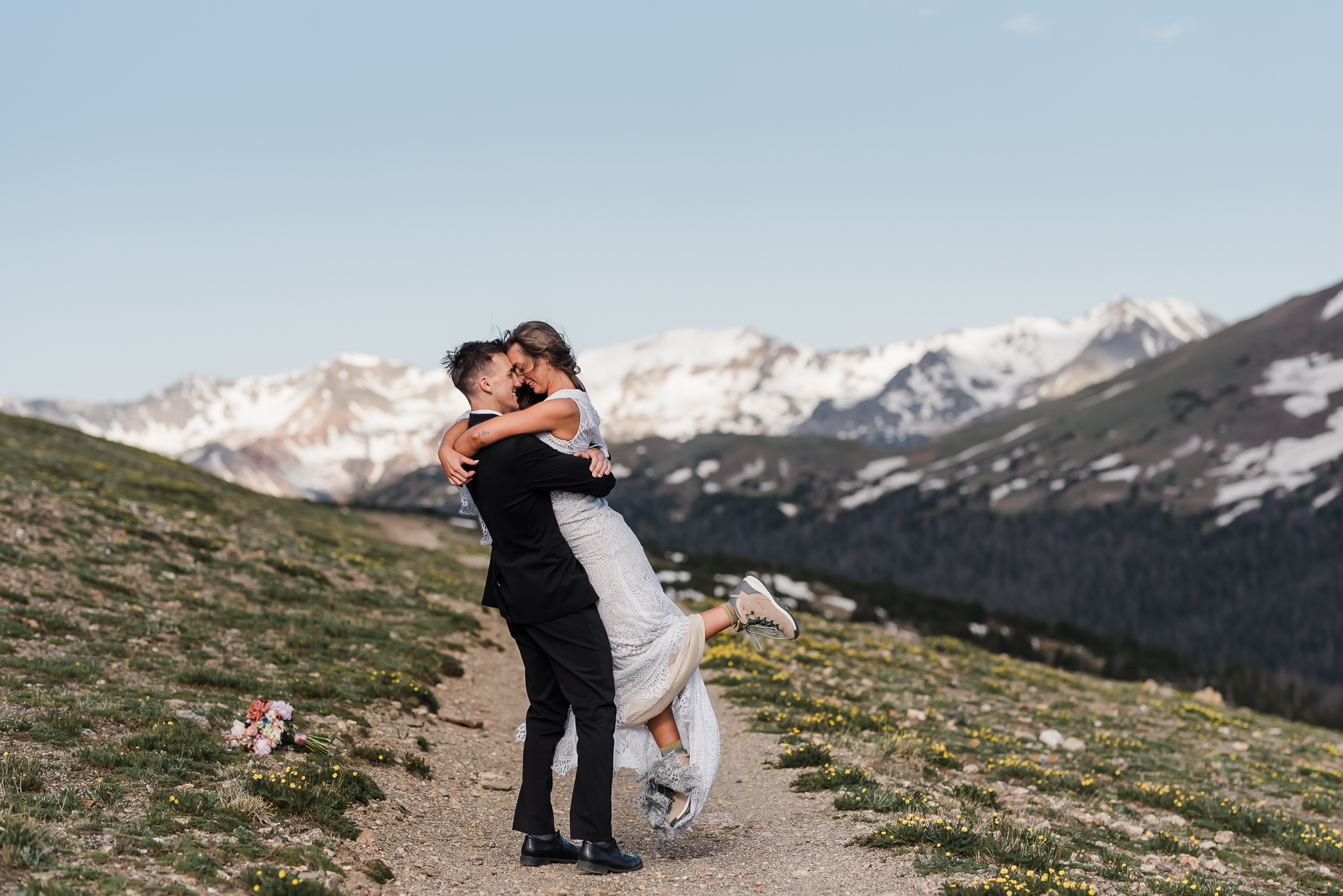 A groom lifts and spins his bride with mountains behind them at their Colorado elopement