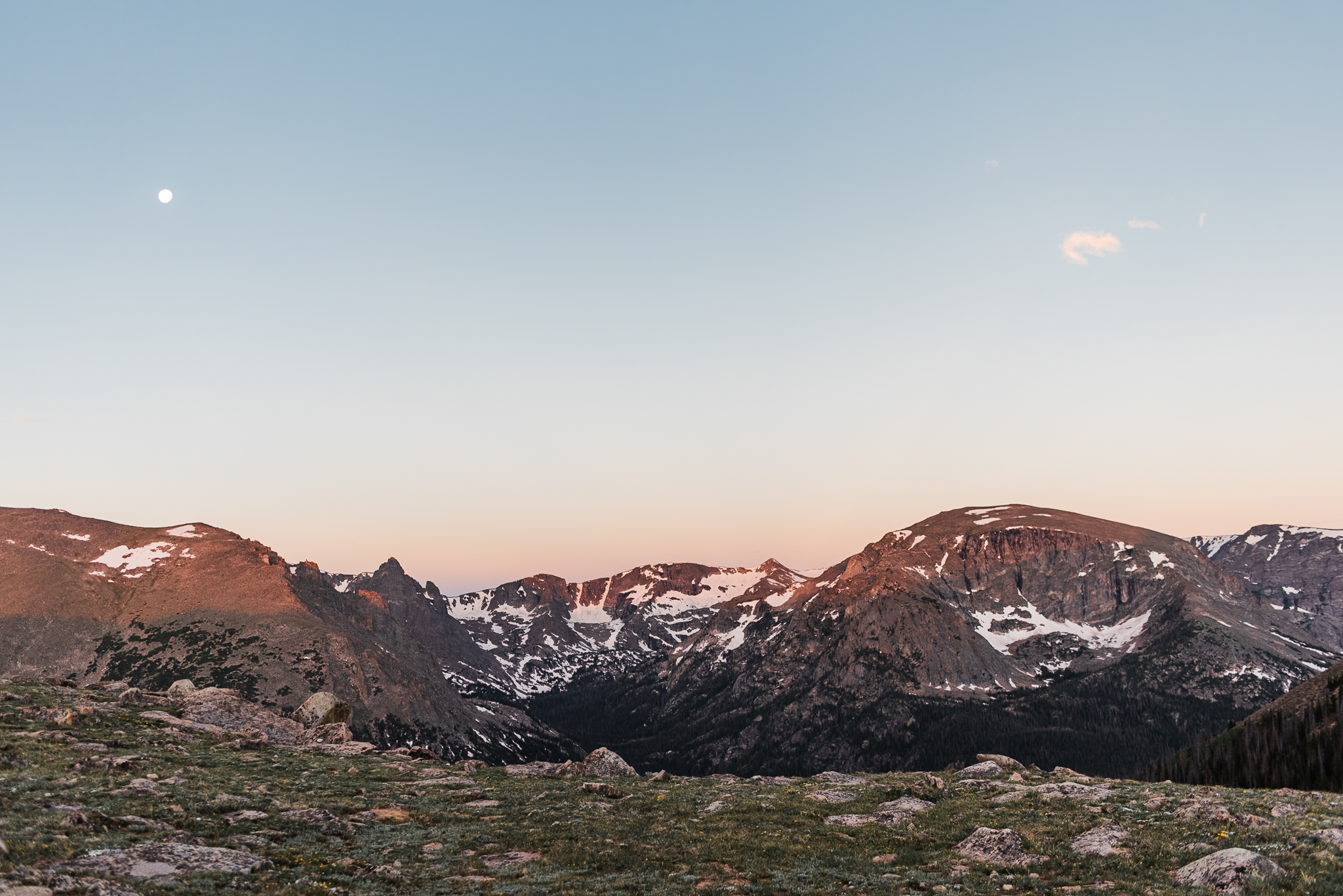 A landscape image of mountains in Rocky Mountain National Park with alpine glow from the rising sun on top of the mountains