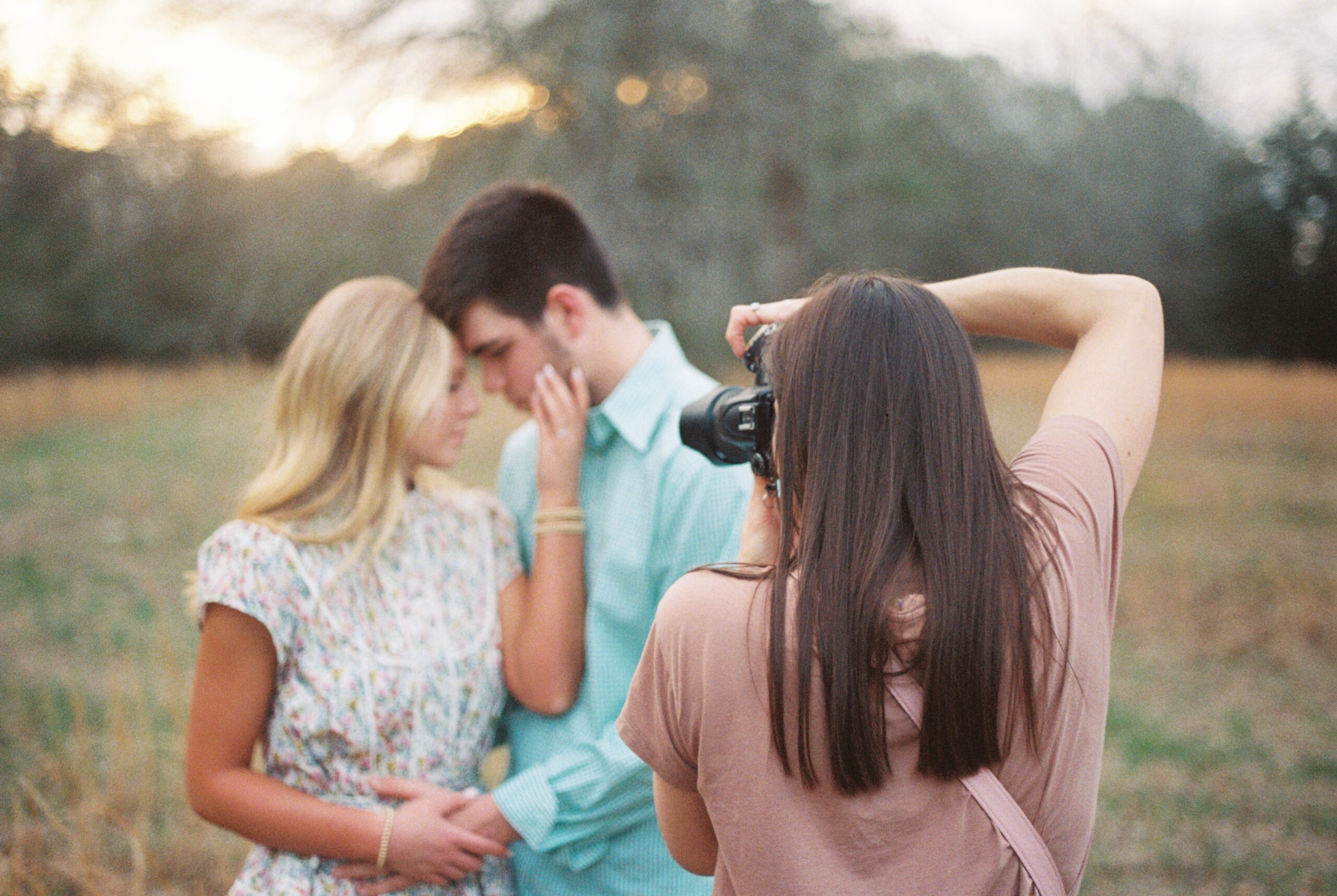 A behind the scenes image of a photographer taking a photo of a newly engaged couple