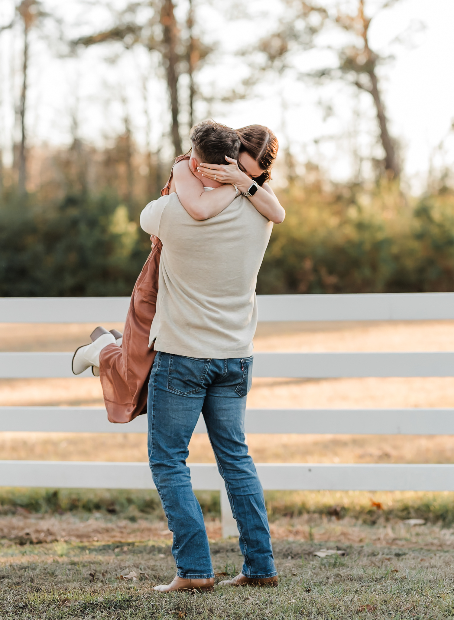 A man lifts his fiance up and spins her around after he proposed to her and she said yes.