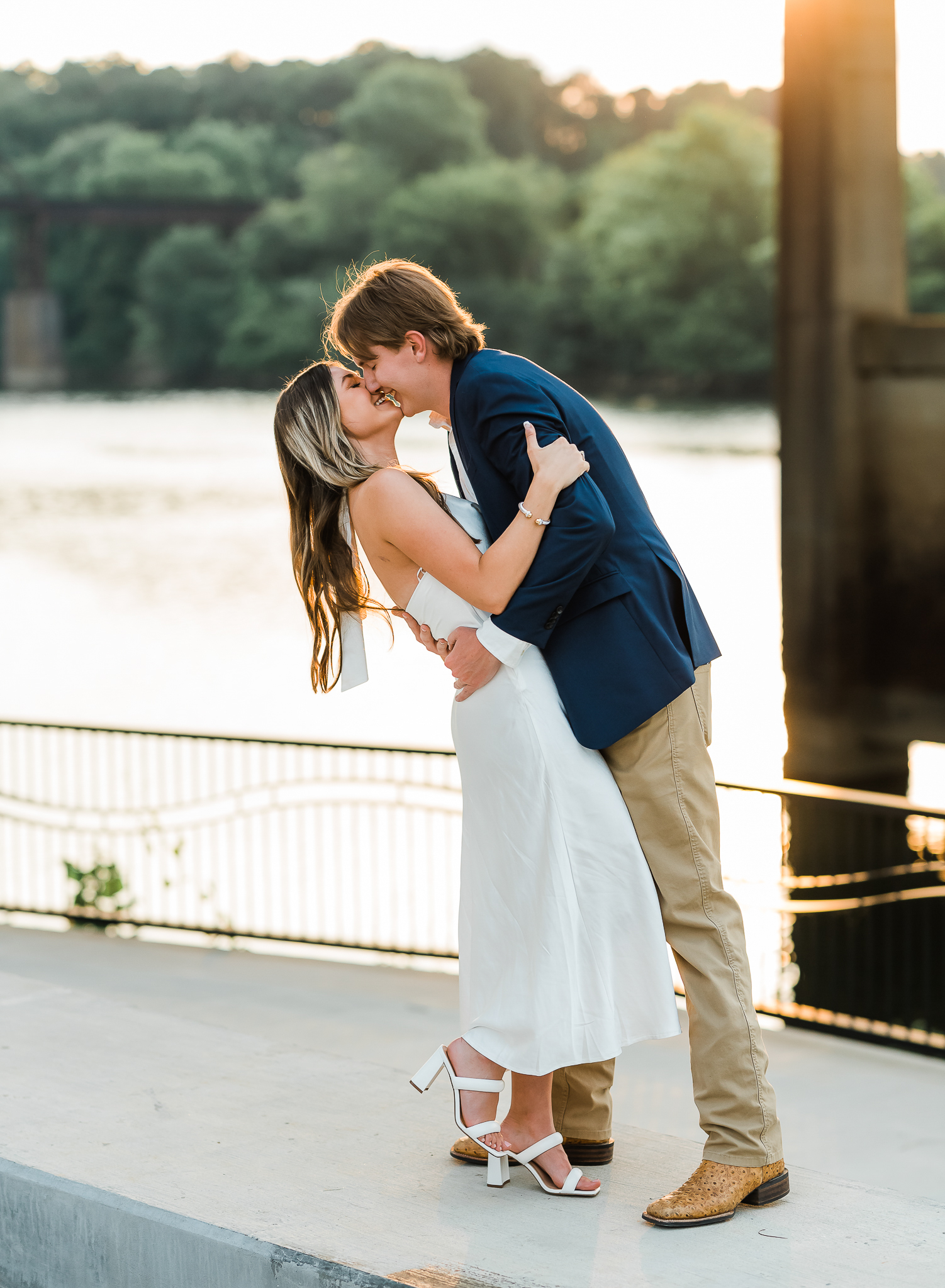 A man and woman embrace after getting engaged on a river walk.