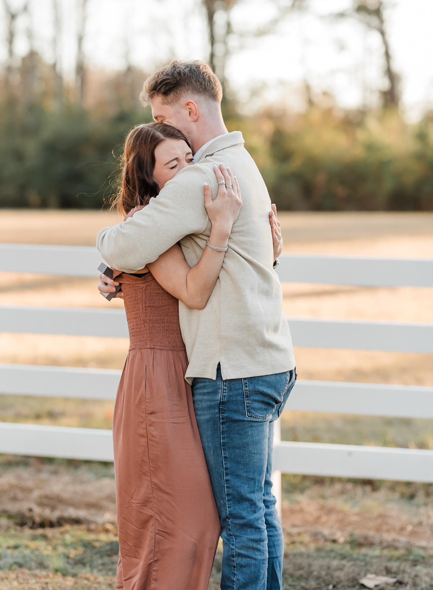 A man and woman hug after the man proposed to the woman and she said yes.