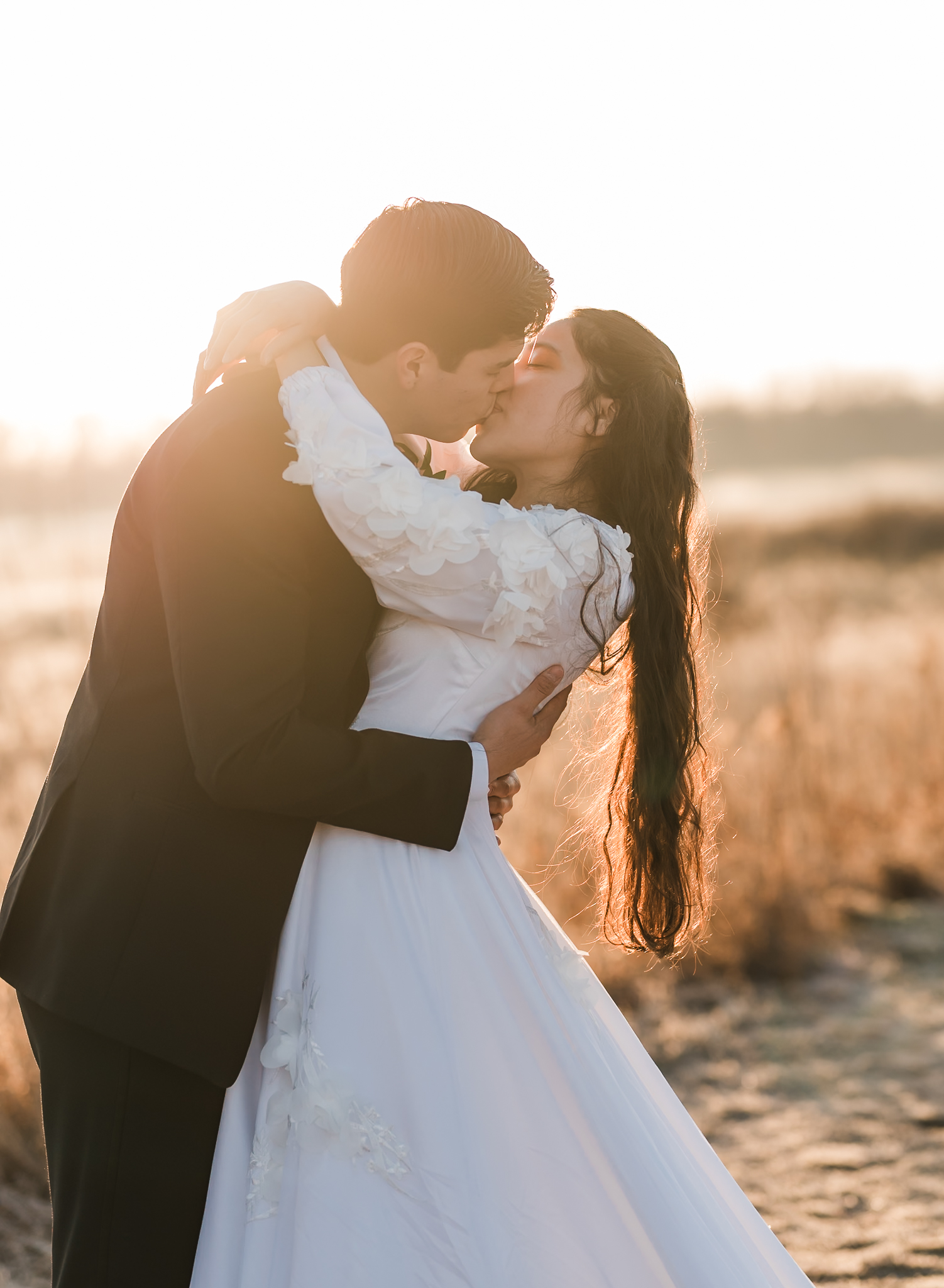 Sunrise elopement with a couple kissing in golden hour light on a wide open plain.