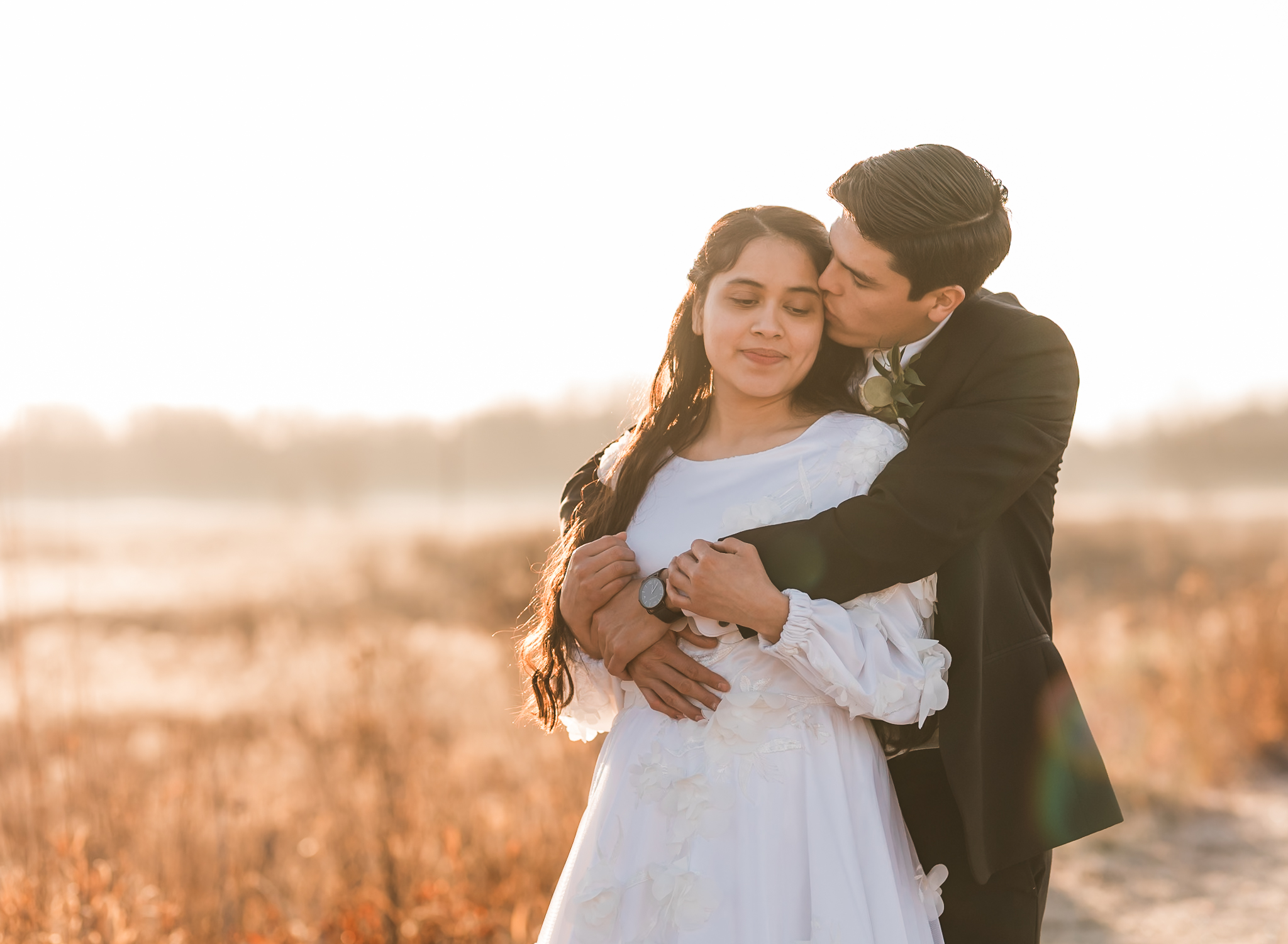 Sunrise elopement with a couple hugging in golden hour light on a wide open plain.