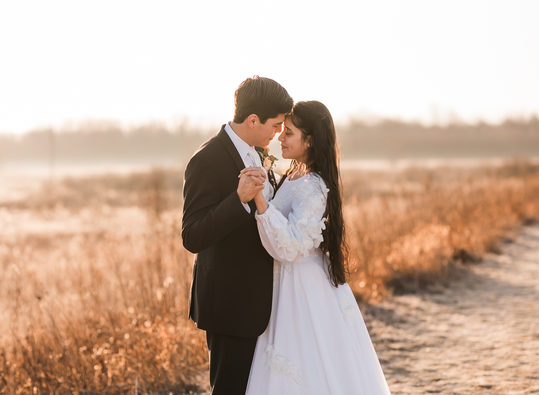 Sunrise elopement with a couple dancing in golden hour light on a wide open plain.
