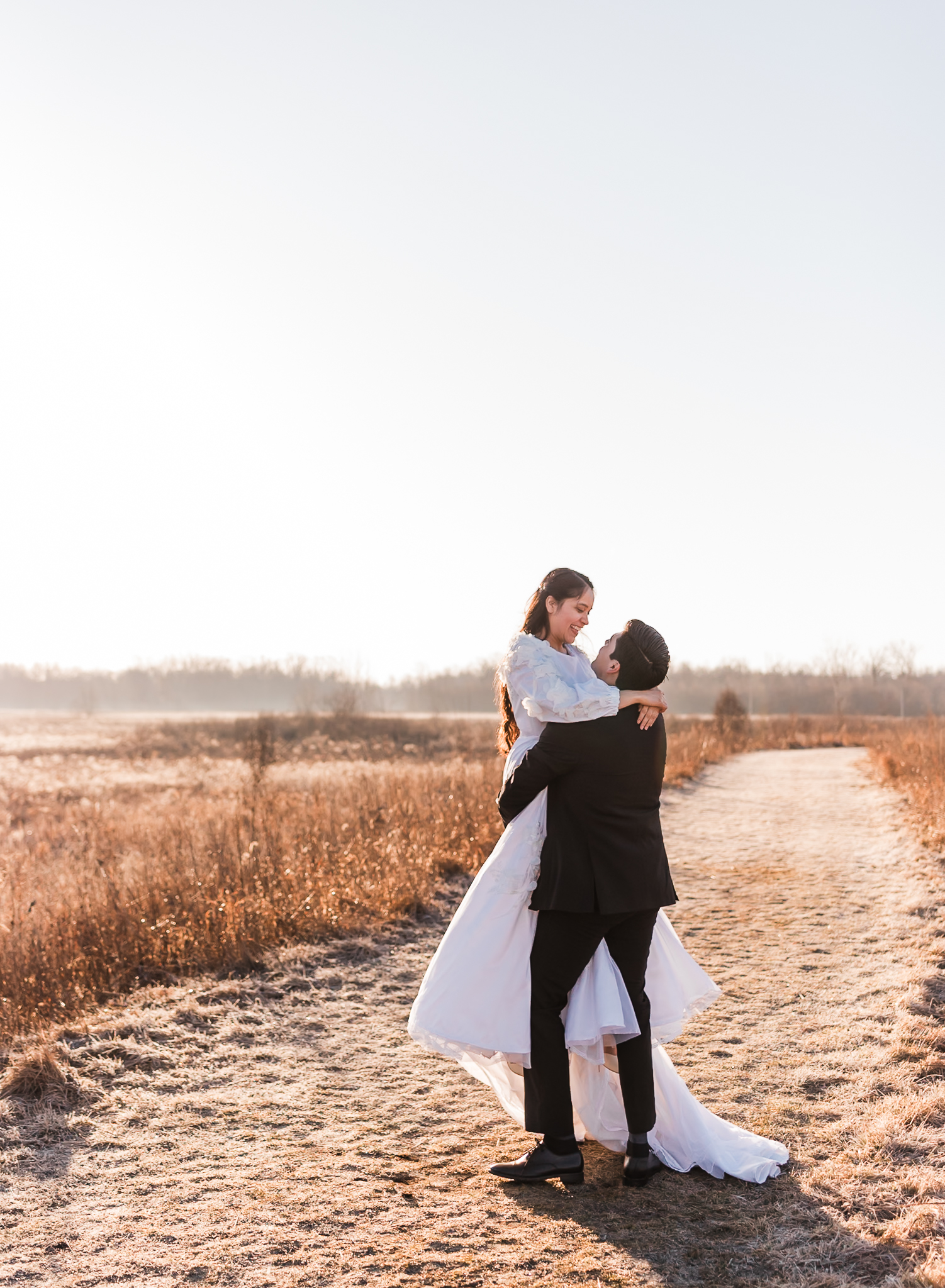 Sunrise elopement with a couple in golden hour light on a wide open plain. The groom is lifting his bride and spinning her.