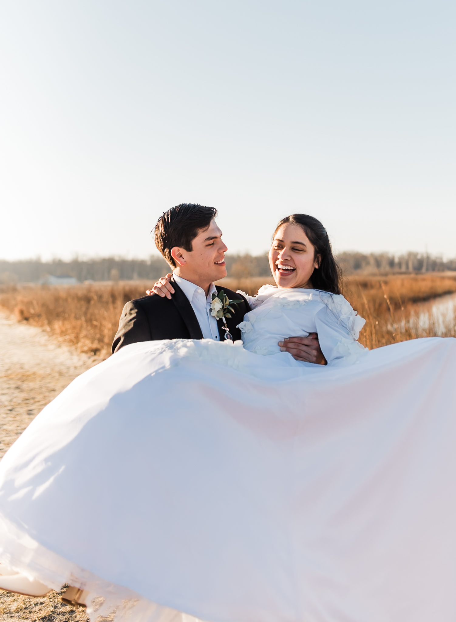 Sunrise elopement with a couple in golden hour light on a wide open plain. The groom is carrying his bride.