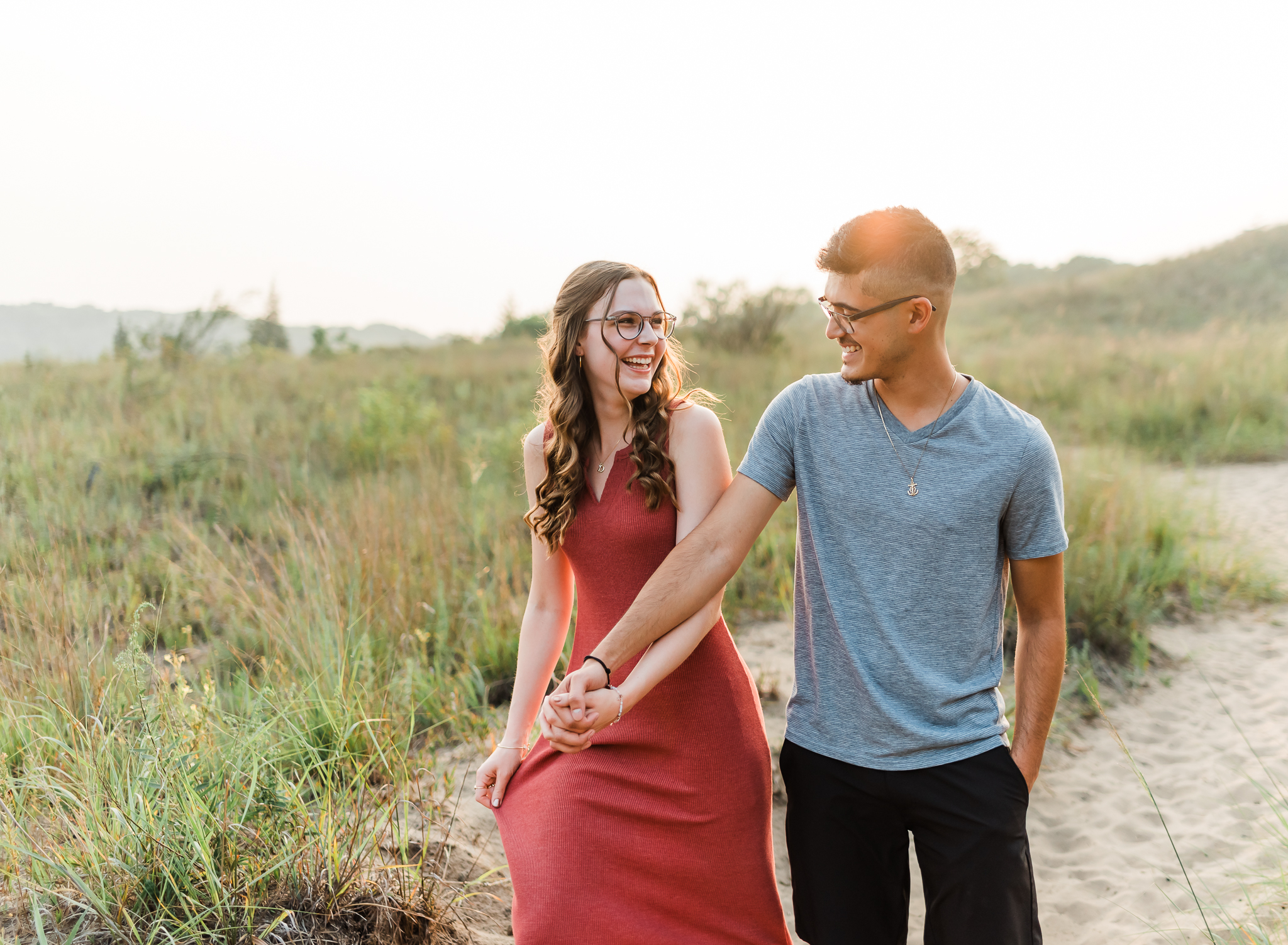 A couple walking hand in hand during their adventure session at Indiana Dunes National Park on Lake Michigan
