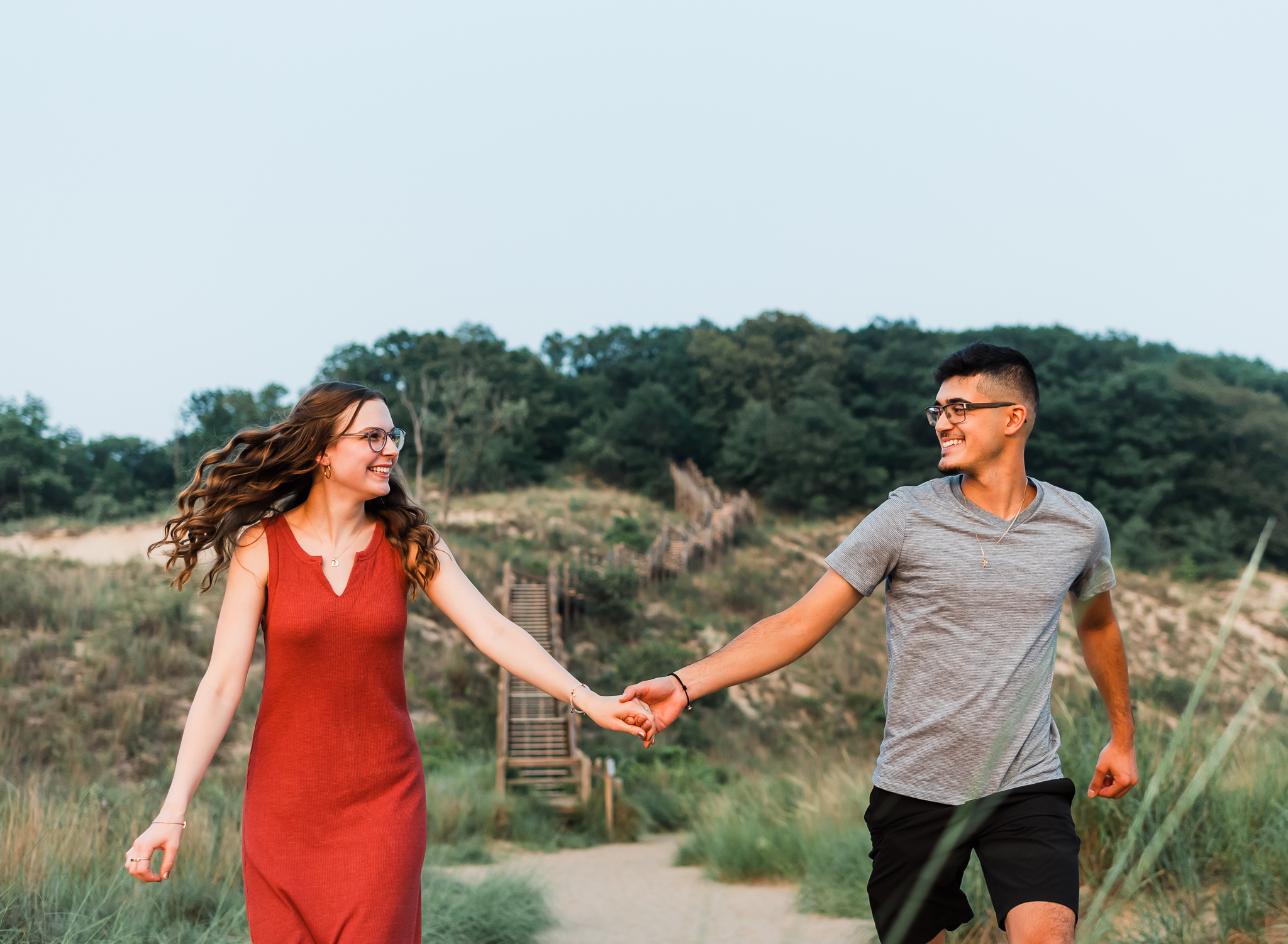 A couple walking hand in hand during their adventure session at Indiana Dunes National Park on Lake Michigan