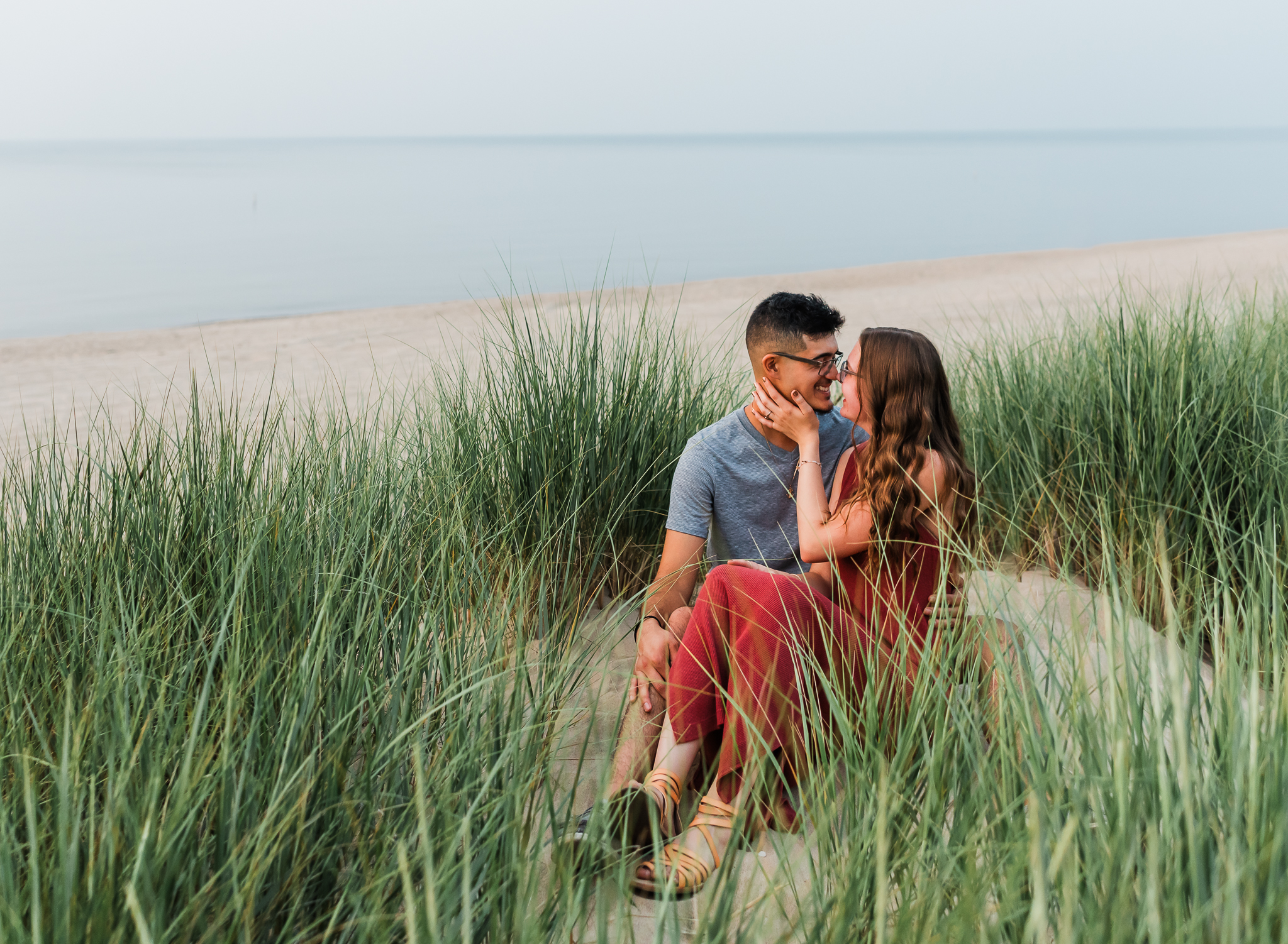 A couple sits together during their adventure session at Indiana Dunes National Park on Lake Michigan