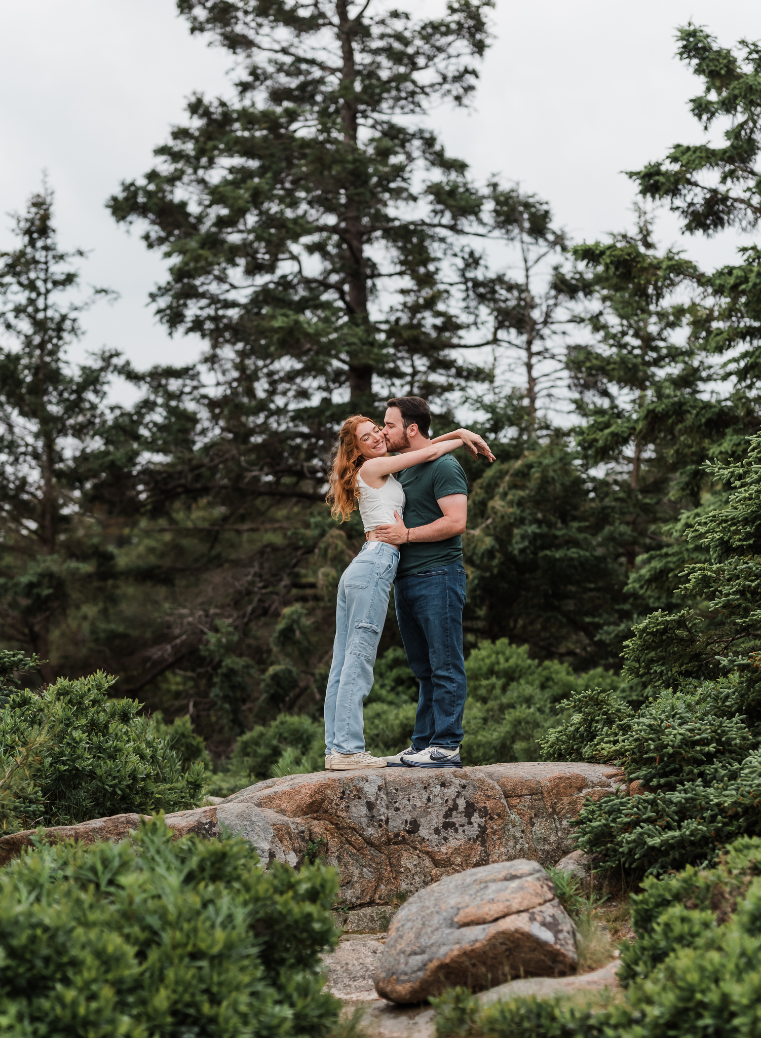 Man and woman embrace on the rocky coast of Acadia National Park in Maine