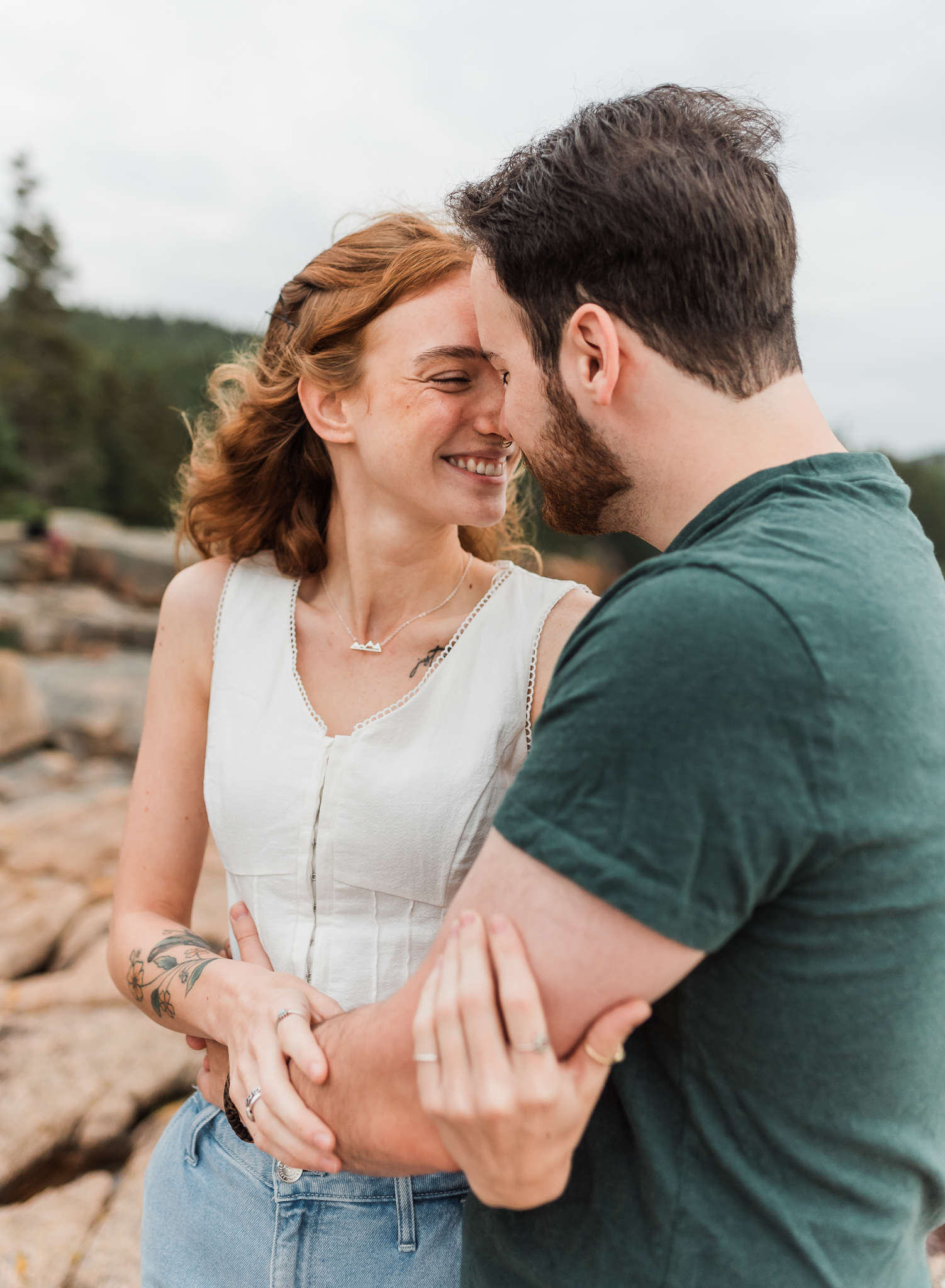 Man and woman embrace on the rocky coast of Acadia National Park in Maine