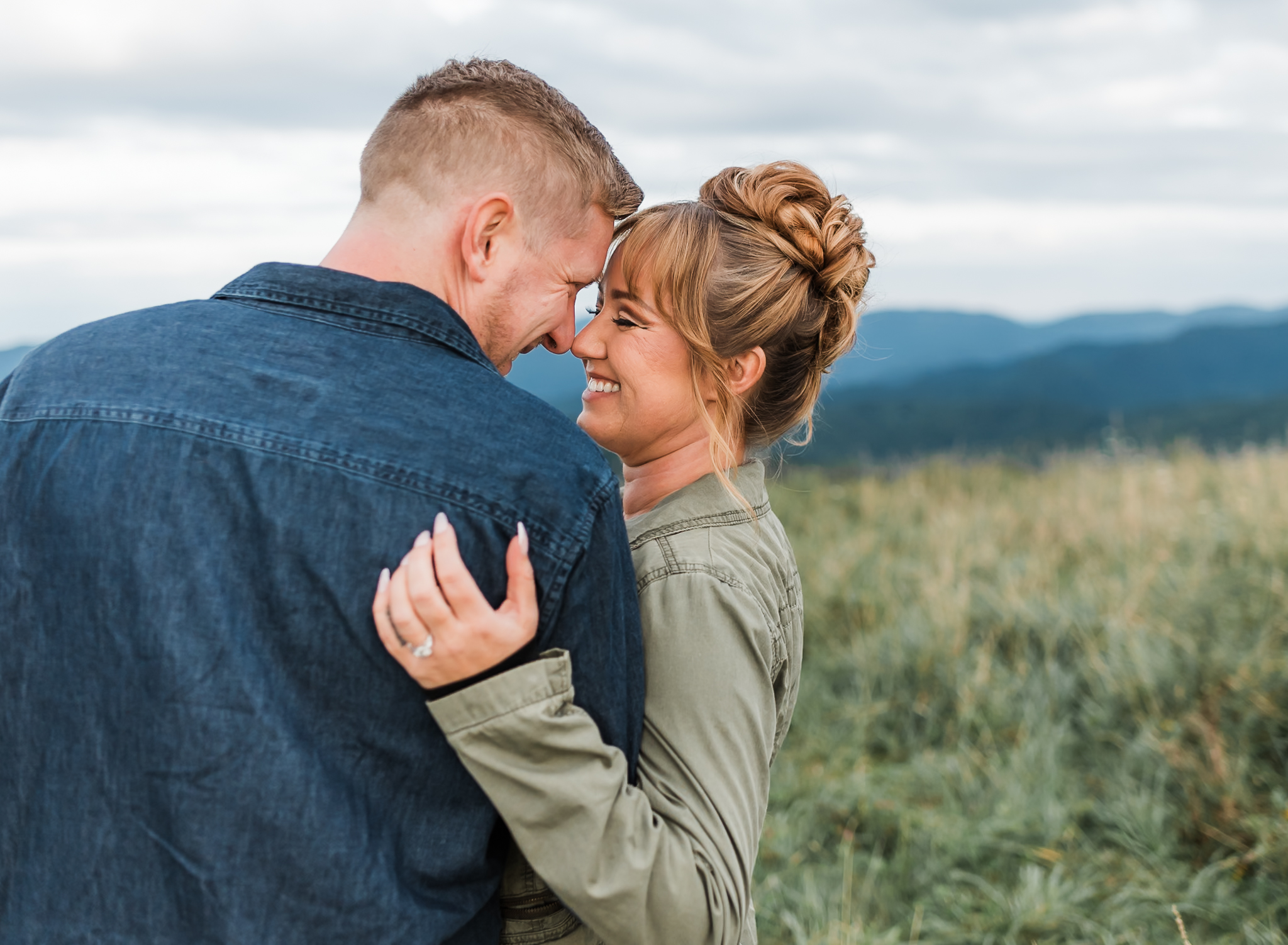 A man and woman touch foreheads and laugh with each other.