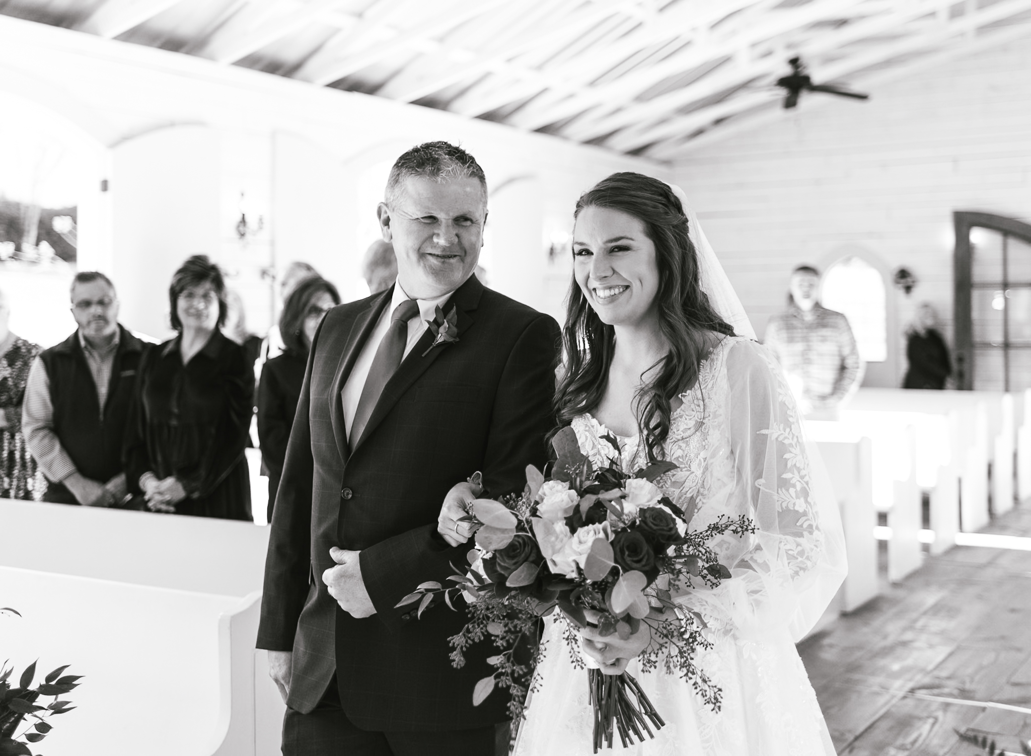 A bride's dad is looking at her while he walks her down the aisle at her intimate wedding. 