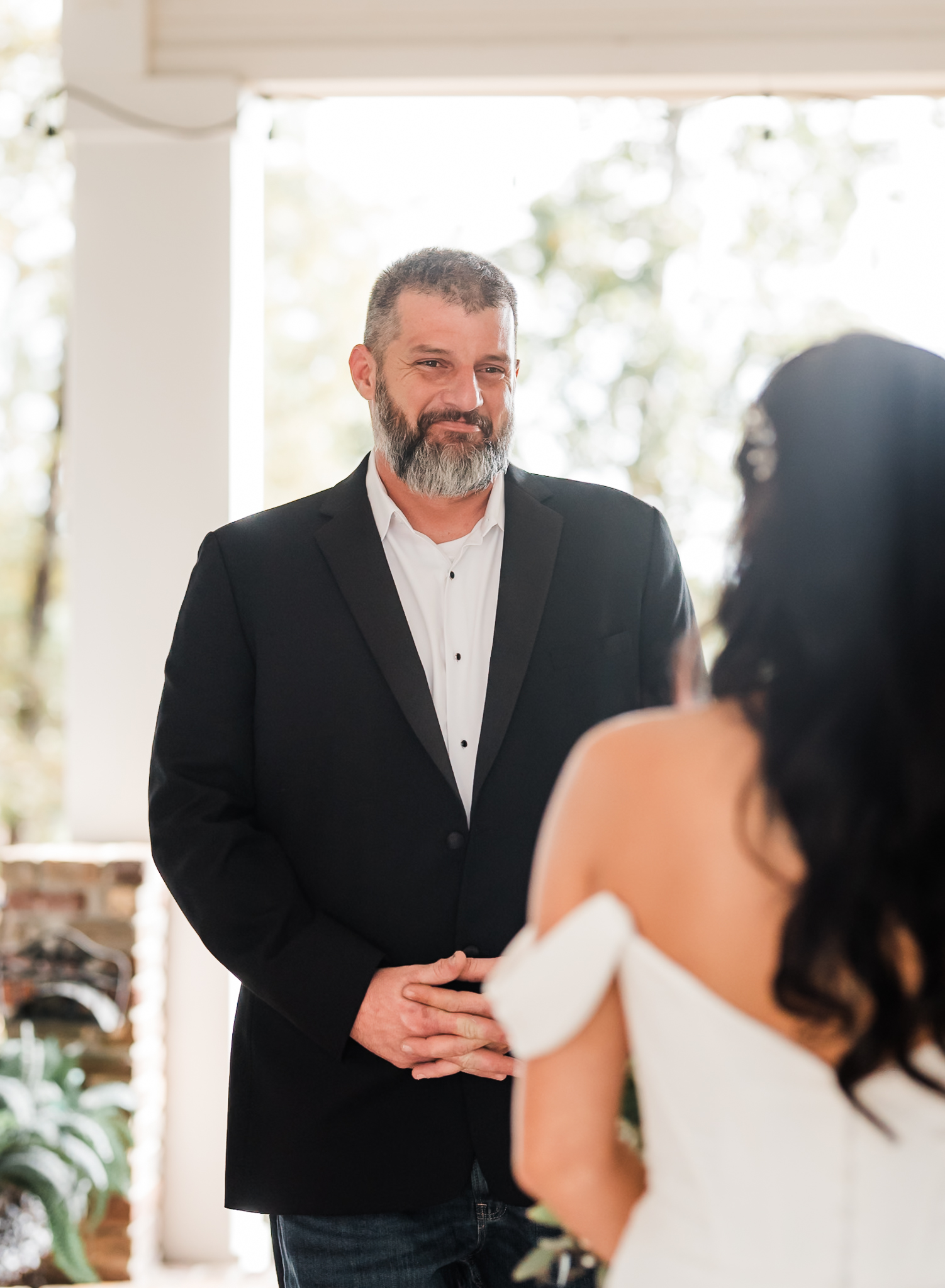 a bride's dad is looking at her with a smile and tears at the first look of her in her wedding dress.