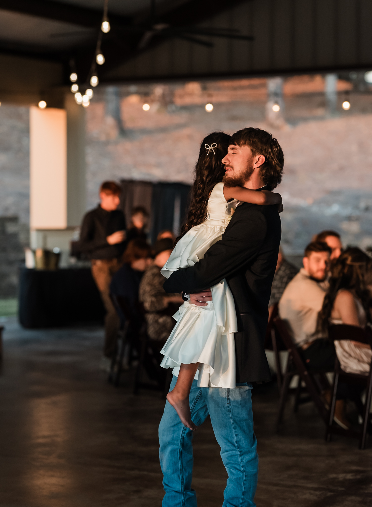 A stepdad dancing with his young daughter at his intimate wedding reception. he is crying.