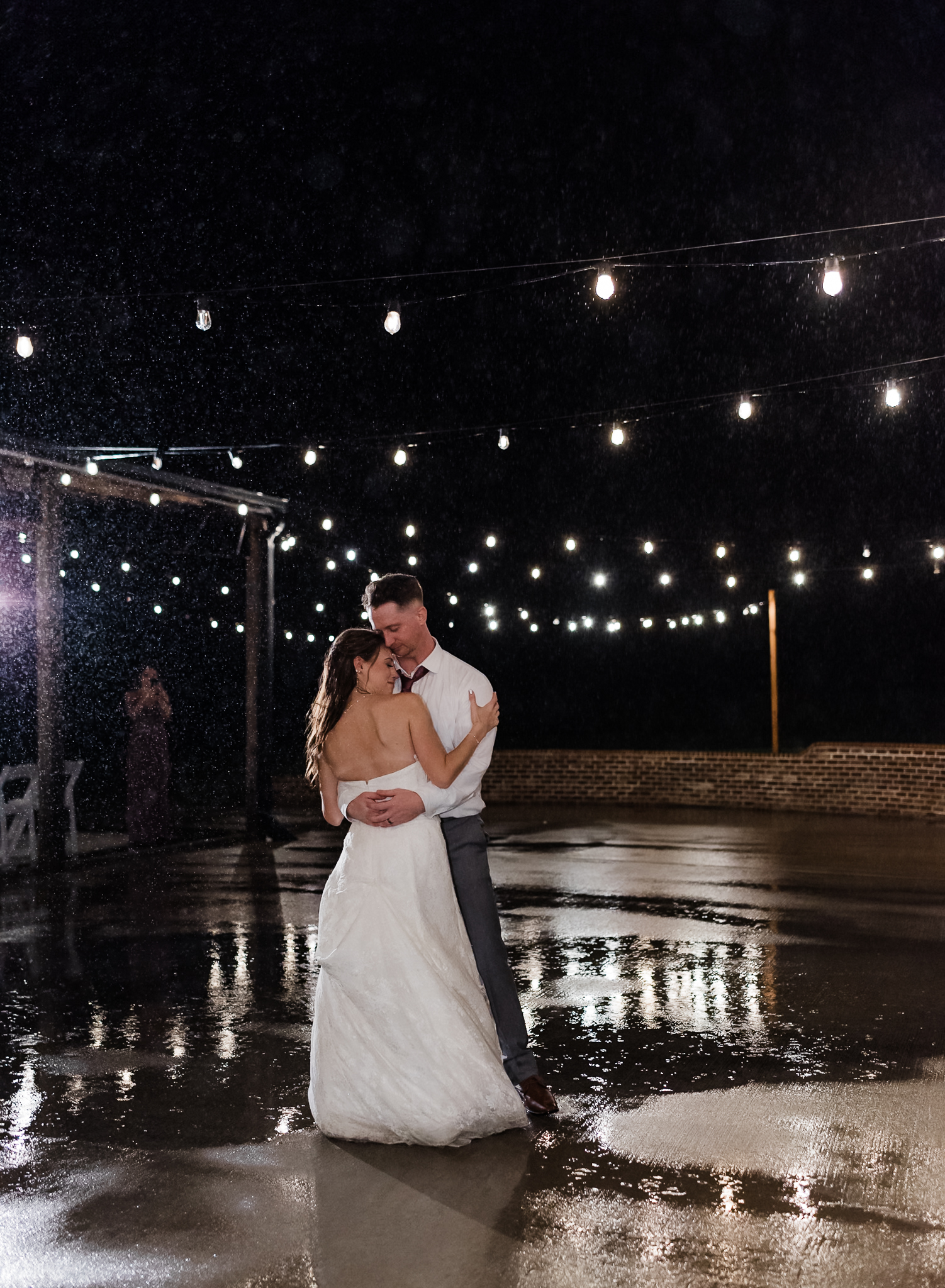 a bride and groom dance in the rain at their intimate wedding 