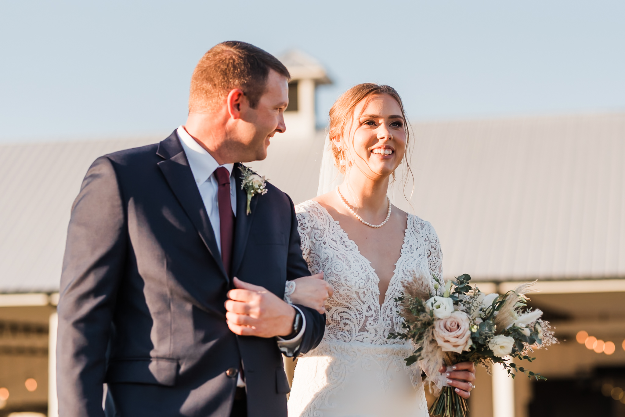 A dad looks lovingly at his daughter as he walks her down the aisle at her intimate wedding. 