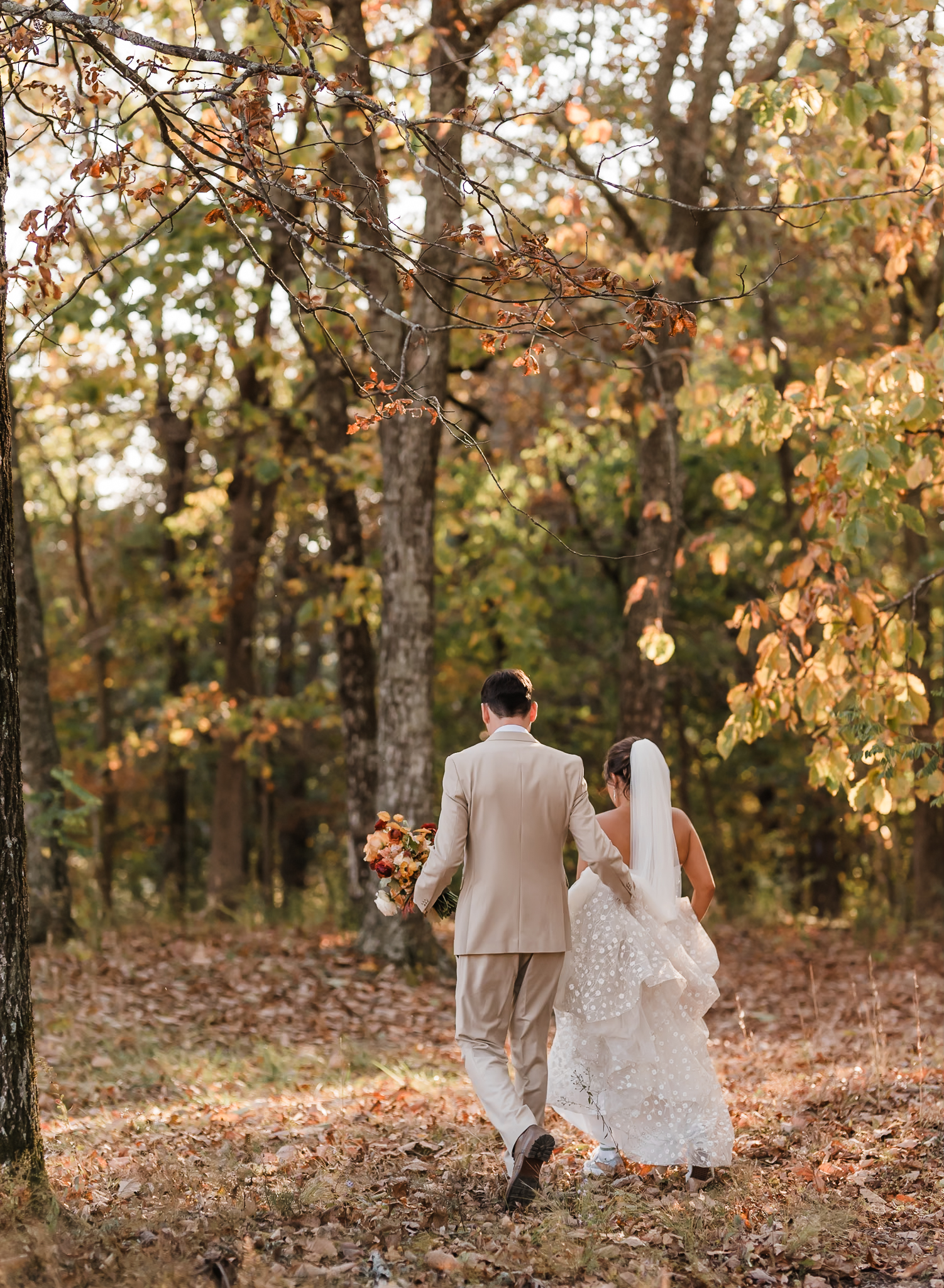 A bride and groom are walking away together and the groom is helping the bride hold her dress at their elopement. 
